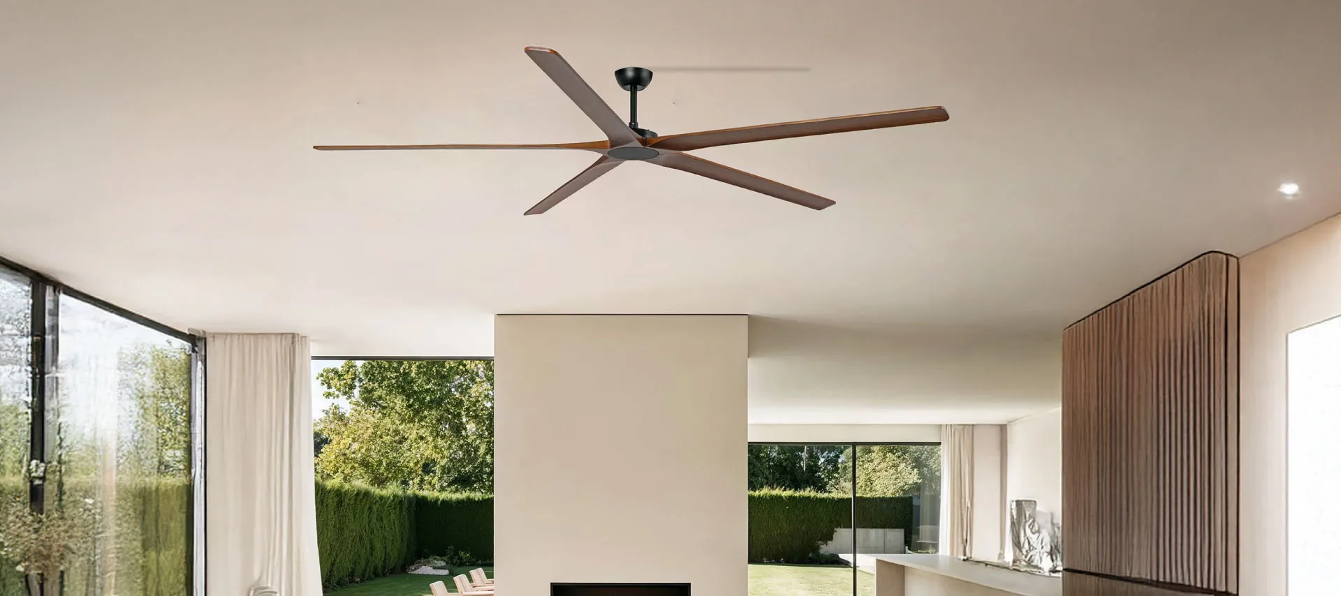 Fans : Brown wooden ceiling fan above a beige-walled living room with a lush garden in the background