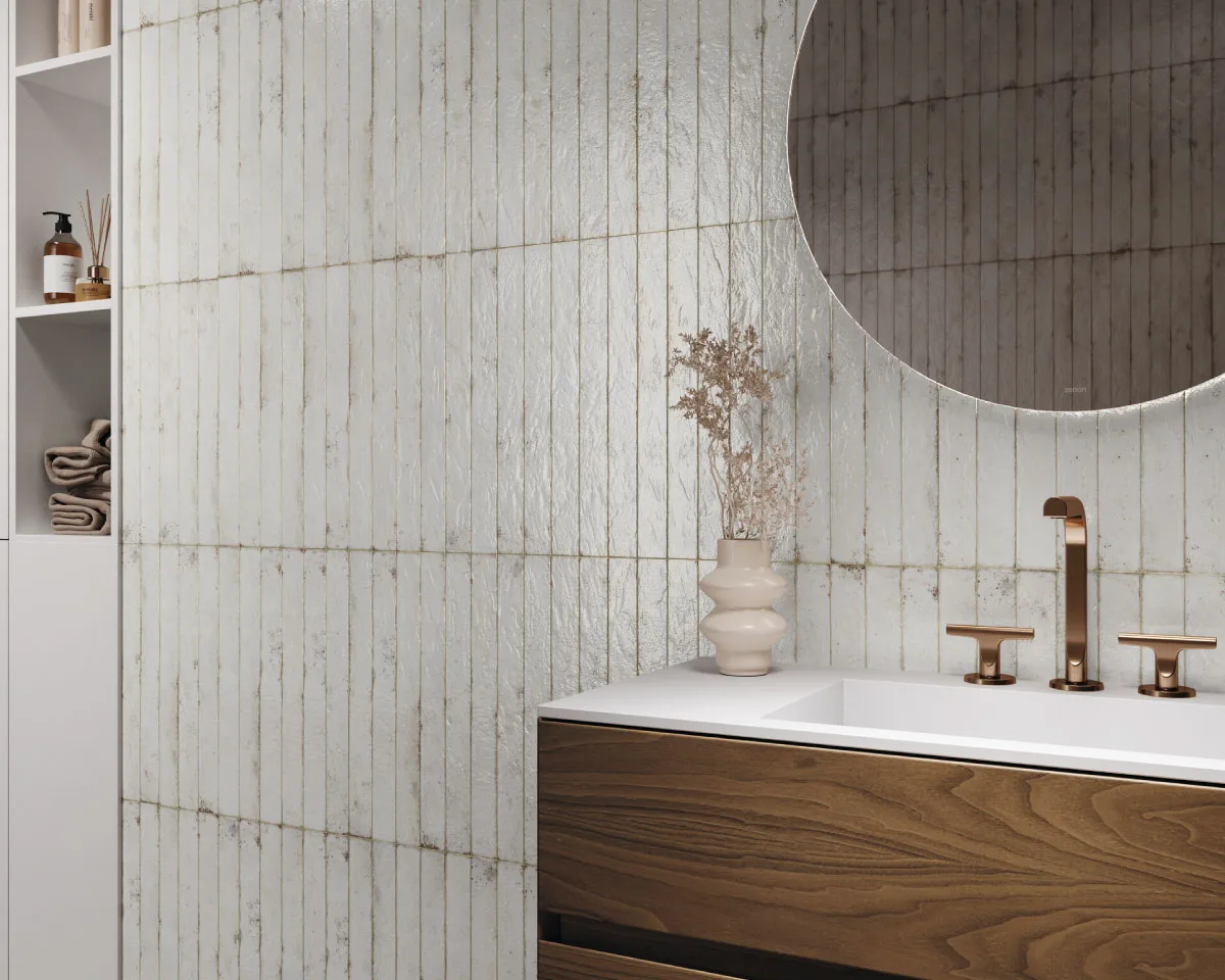 Modern bathroom with textured white vertical ceramic wall tiles, floating walnut wood vanity, white integrated sink, brushed bronze faucet, round backlit mirror, and minimalist décor in a contemporary luxury interior.