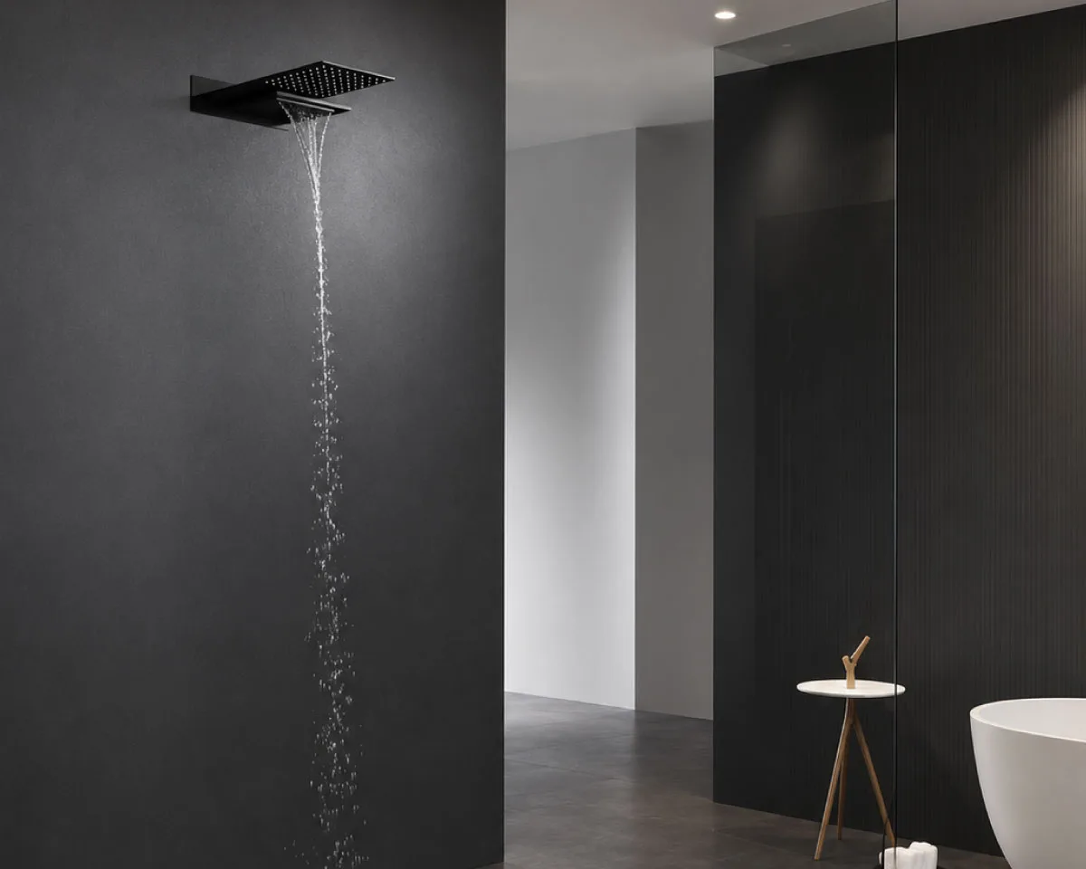 Minimalist matte black waterfall shower head with flowing water installed in a luxurious contemporary bathroom featuring dark textured walls and elegant freestanding bathtub.