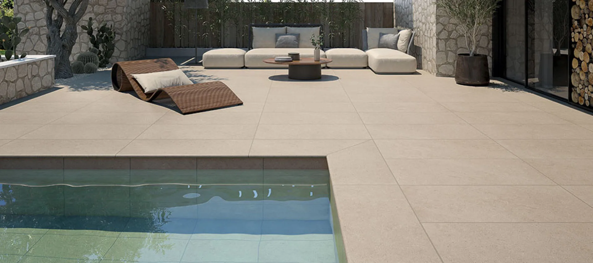 Modern luxury terrace featuring large beige porcelain outdoor floor tiles surrounding a swimming pool with natural stone walls and contemporary lounge furniture.
