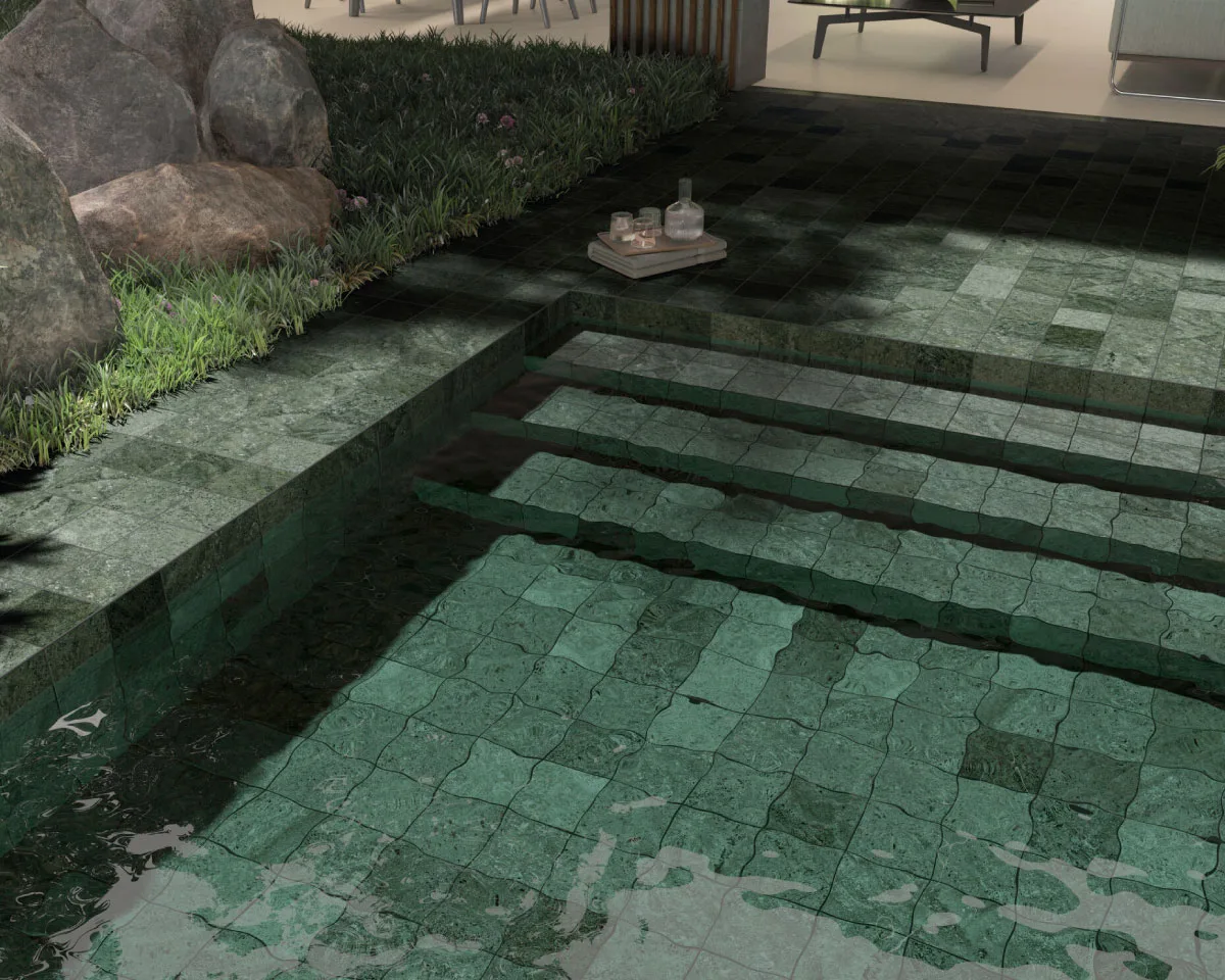 Luxury swimming pool finished with emerald green porcelain tiles, wide submerged steps and matching outdoor paving surrounded by landscaped greenery.
